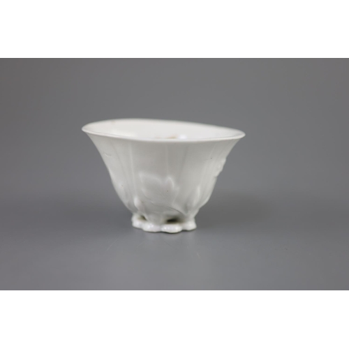 217 - A Chinese Dehua blanc de chine libation cup, moulded as a curled leaf with with leaves, buds and but... 