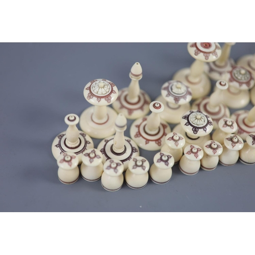 22 - A 19th century Muslim ivory chess set, the two sides with engraved red and brown geometric motifs, k... 