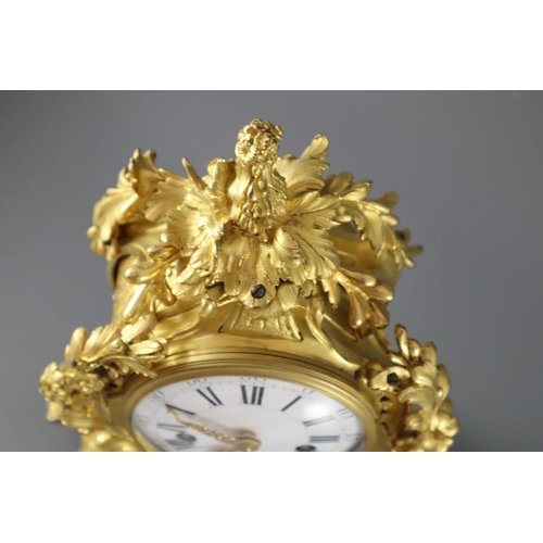 295 - A mid 18th century French ormolu mantel clock, with ornate pierced foliate scroll case and enamelled... 