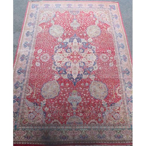 307 - A Kirman carpet, the claret field with overall flowering shrub and palmette design centred by an ind... 