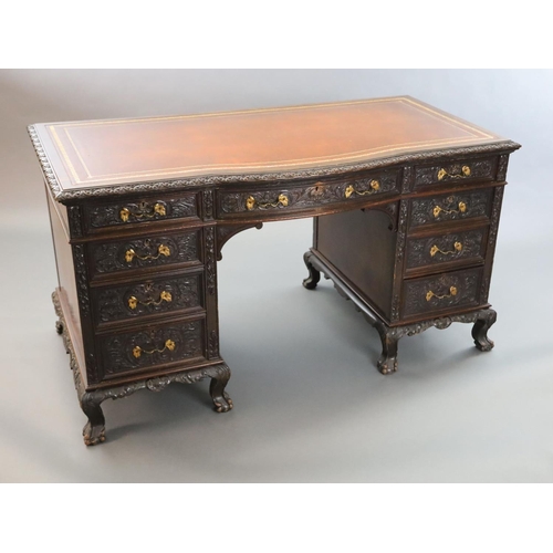 373 - An Edwardian foliate carved mahogany serpentine kneehole desk, with gilt brown skiver, central bowfr... 