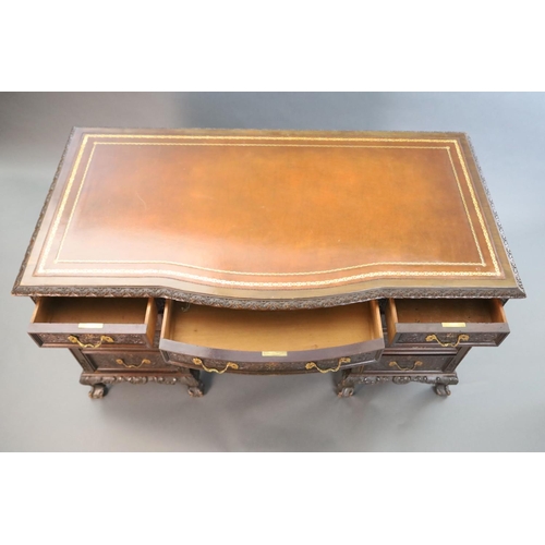 373 - An Edwardian foliate carved mahogany serpentine kneehole desk, with gilt brown skiver, central bowfr... 