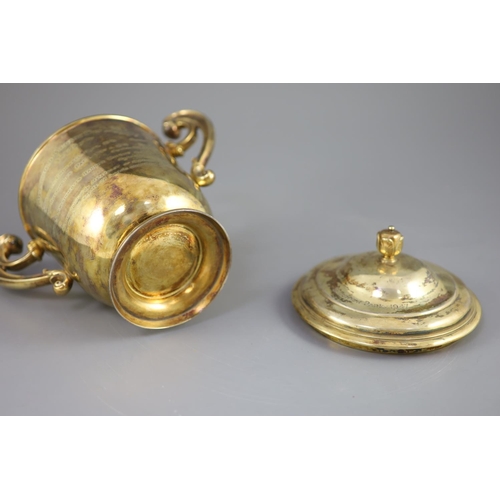 506 - An Edwardian silver gilt-lidded two handled presentation cup and cover, by R & S Garrard and Co. wit... 