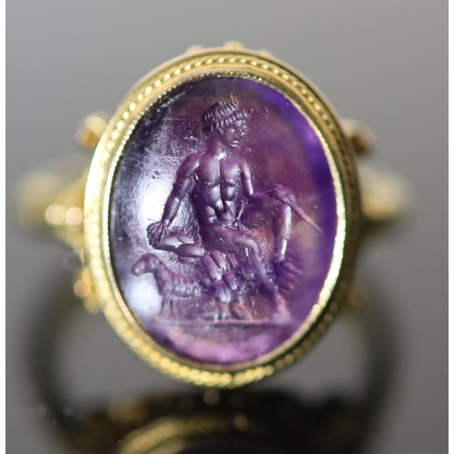 532 - A 19th century style gold ring set with an antique intaglio oval amethyst, carved with a seated figu... 