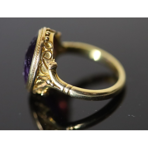 532 - A 19th century style gold ring set with an antique intaglio oval amethyst, carved with a seated figu... 