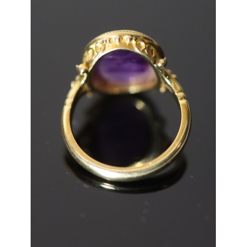 532 - A 19th century style gold ring set with an antique intaglio oval amethyst, carved with a seated figu... 