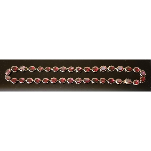 538 - An early 19th century gold and garnet set necklace, set with thirty six oval cut garnets, 38cm, gros... 