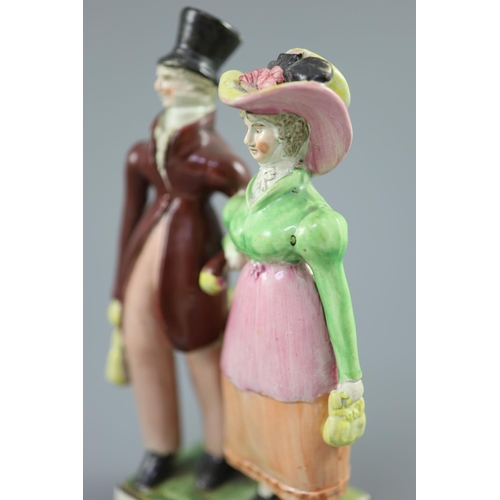 54 - A Staffordshire pearlware group of a Dandy and Dandizette, c.1820, standing before rockwork on a bla... 