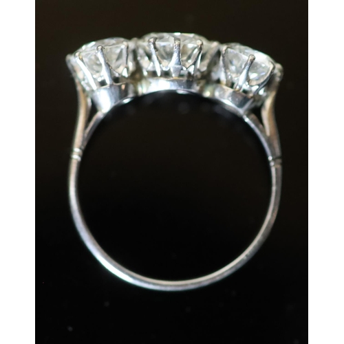 591 - A platinum and three stone diamond ring, the central stone weighing approximately 1.20ct and the two... 