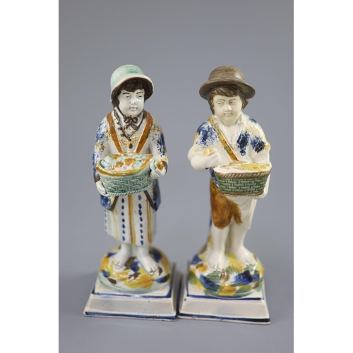 66 - A pair of Prattware figures of fruit and biscuit street vendors, c.1790-1800, on square bases, pearl... 