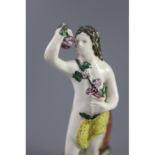 68 - An enamelled creamware figure of Bacchus, attributed Leeds Pottery, c.1790-1800, standing by wine ba... 