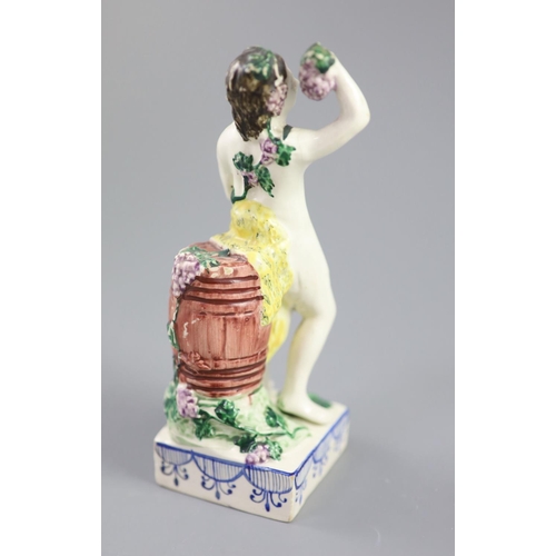 68 - An enamelled creamware figure of Bacchus, attributed Leeds Pottery, c.1790-1800, standing by wine ba... 