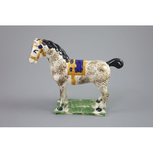 71 - A North Country pearlware figure of a dapple horse with blue saddle, c.1800-20 on a slab base, 14.5c... 