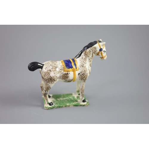 71 - A North Country pearlware figure of a dapple horse with blue saddle, c.1800-20 on a slab base, 14.5c... 