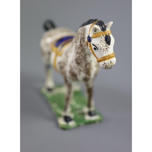 71 - A North Country pearlware figure of a dapple horse with blue saddle, c.1800-20 on a slab base, 14.5c... 