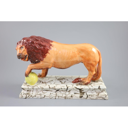 72 - An Enoch Wood pearlware figure of a Medici Lion, c.1800-10, with paw on a golden ball, on a marbled ... 