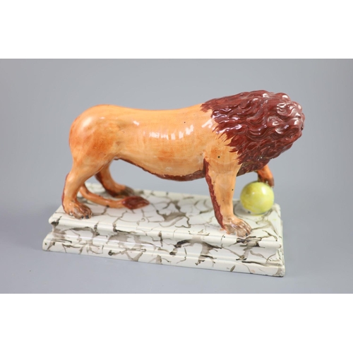 72 - An Enoch Wood pearlware figure of a Medici Lion, c.1800-10, with paw on a golden ball, on a marbled ... 