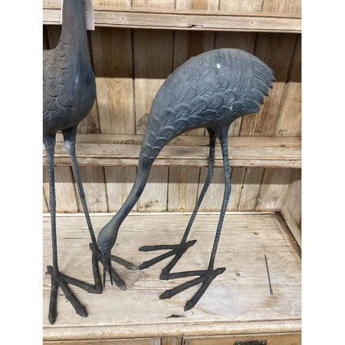 10 - A pair of patinated cast metal garden cranes, larger 91cm high