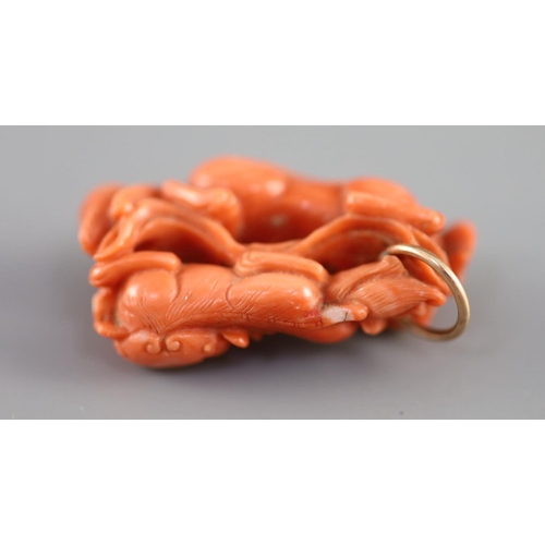 127 - A Chinese coral lion-dog pendant, 19 century,carved in high relief and openwork with two lion-dogs... 