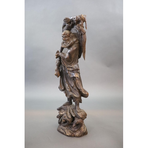 128 - A large Chinese carved hardwood figure of a Luohan, 20th century,holding a Buddhist rosary, with the... 