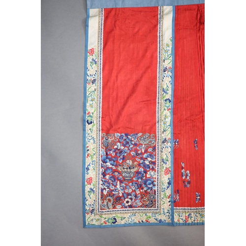 173 - A 19th century Chinese red ground silk skirt,embroidered with blue flowers and auspicious symbols in... 