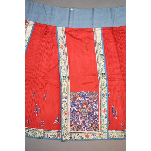 173 - A 19th century Chinese red ground silk skirt,embroidered with blue flowers and auspicious symbols in... 