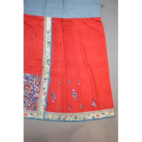 173 - A 19th century Chinese red ground silk skirt,embroidered with blue flowers and auspicious symbols in... 