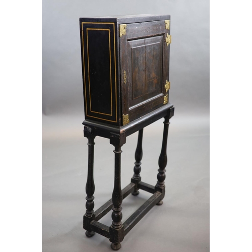 232 - An early 18th century European japanned cabinet on stand,the single panelled door with gilt brass mo... 