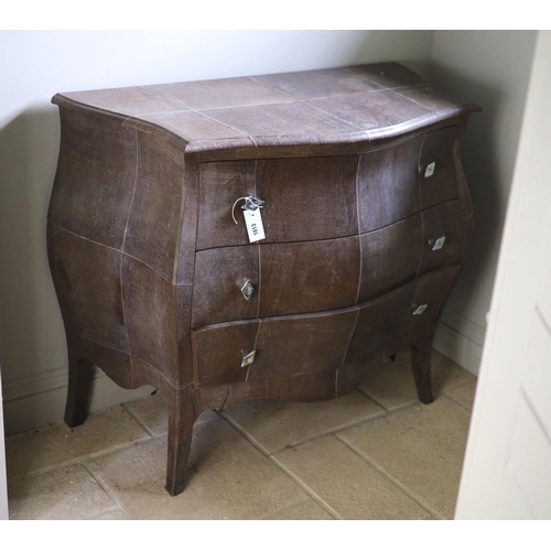 A three drawer bombe commode, upholstered in simulated snake skin