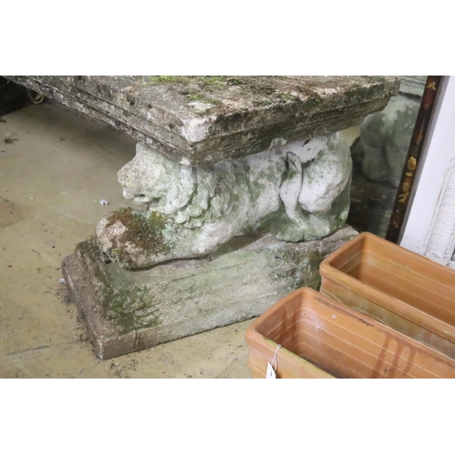 142 - A pair of reconstituted stone garden benches of curved rectangular form with recumbent lion supports... 