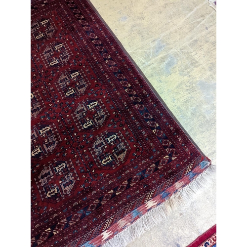 182 - A Belouch red ground rug woven with octagonal motifs,  190 x 124 cms.