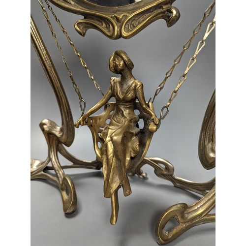 409 - An Art Nouveau style mirror with model of girl sitting on a swing, height 45cm