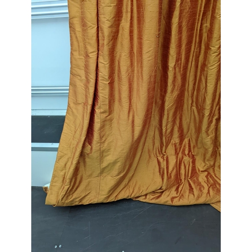 86 - A pair of orange lined curtains. Approximate measurements: Width of top 180cm, Width of bottom 320cm... 