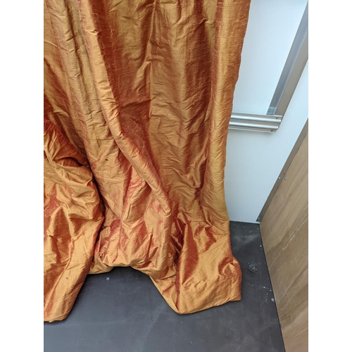 86 - A pair of orange lined curtains. Approximate measurements: Width of top 180cm, Width of bottom 320cm... 