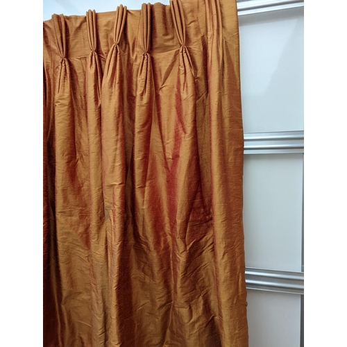 86 - A pair of orange lined curtains. Approximate measurements: Width of top 180cm, Width of bottom 320cm... 