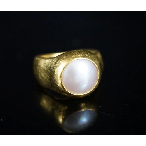 960 - A planished yellow metal (inscribed 24k) and mother of pearl mounted ring, indistinctly signed, size... 