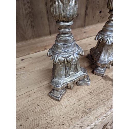 130 - A pair of 18th century style carved silvered wood candlesticks, height 58cm