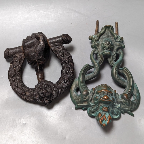 297 - A grotesque bronze door knocker, 23 cm high and a similar cast-iron example