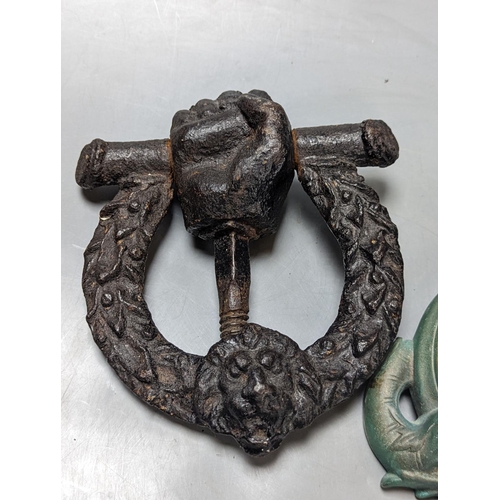 297 - A grotesque bronze door knocker, 23 cm high and a similar cast-iron example