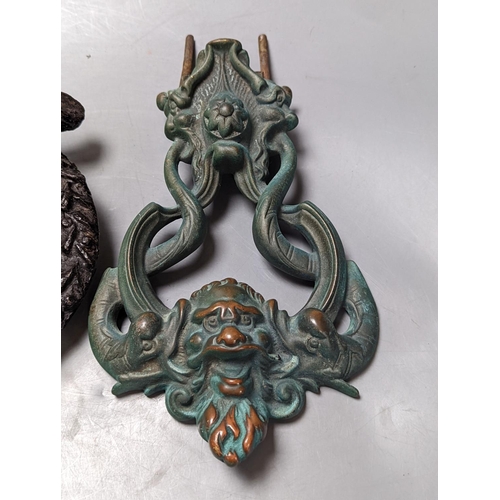 297 - A grotesque bronze door knocker, 23 cm high and a similar cast-iron example