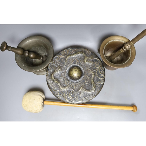 422 - Two pestles and mortars and a Chinese gong with beater, gong 21 cms wide.