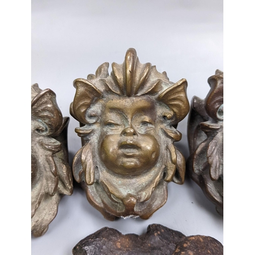 528 - A set of three cast bronze mask-form furniture mounts, 9cm. high,   