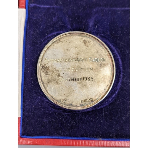 529 - A silver Guildhall School elocution medal, 1935, and a humorous watercolour