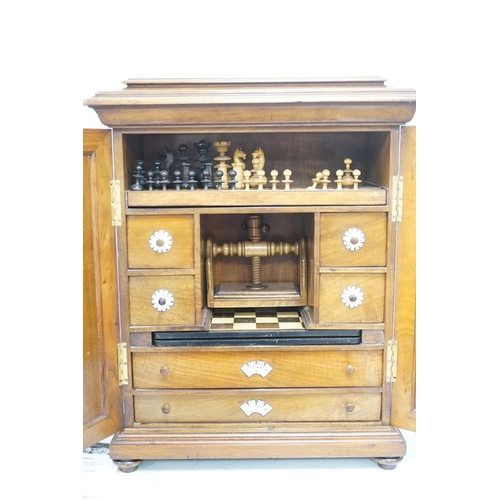 1422 - A late 19th century gilt metal mounted walnut games cabinet,with two panelled doors enclosing slidin... 