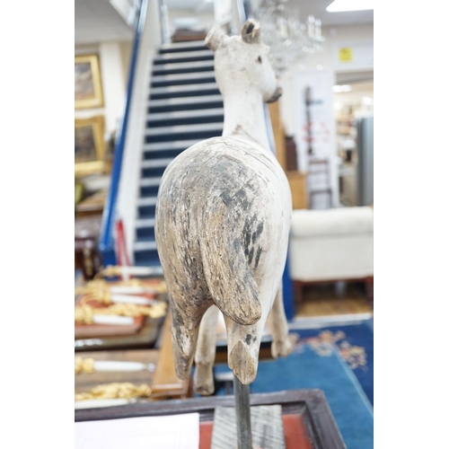 1590 - A carved and painted wood model of a goat, with distressed paint, on stand. 66cm