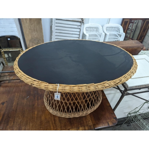 1079 - An oval rattan conservatory table, length 100cm, depth 71cm, height 60cm