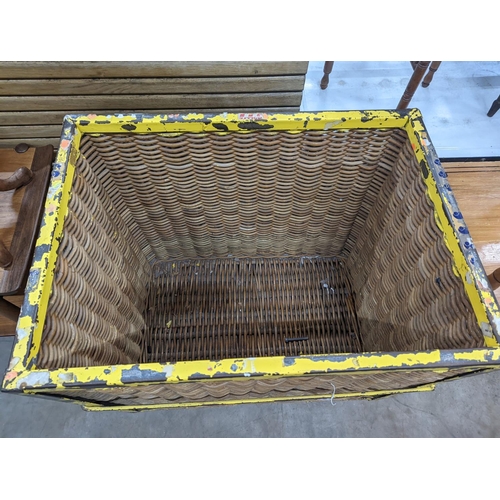 1096 - A vintage wicker and iron laundry basket on wheels, width 85cm, depth 61cm, height 87cm