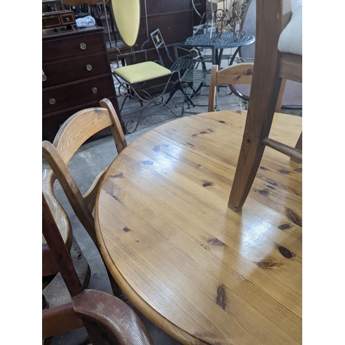 1106 - A reproduction circular pine breakfast table, diameter 105cm, height 77cm together with five pine di... 