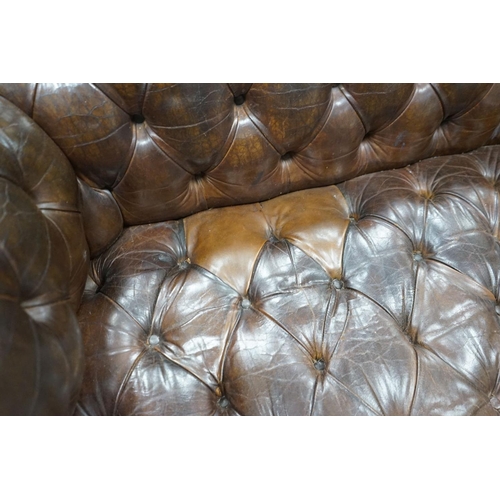 1193 - An early 20th century Chesterfield settee upholstered in deep buttoned brown leather, length 200cm, ... 