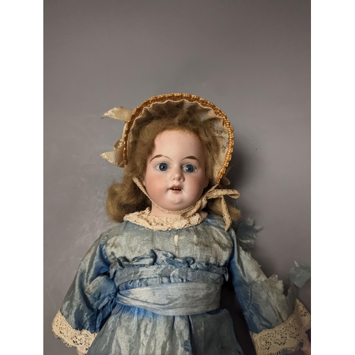 1378 - A German bisque headed doll, wearing a blue silk dress and straw bonnet, 42 cms high.